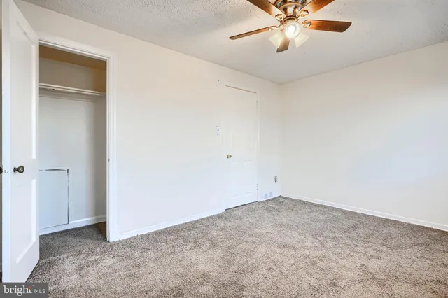 an empty room with closet and a chandelier fan