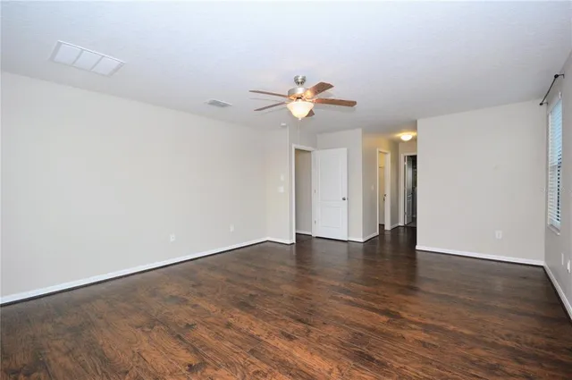 a view of an empty room with a window and wooden floor