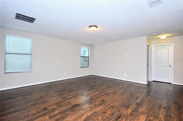 an empty room with wooden floor and windows