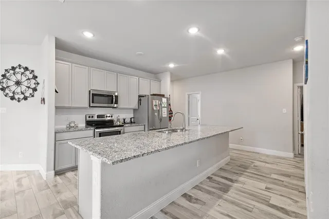 a large kitchen with stainless steel appliances lots of counter space and wooden floor