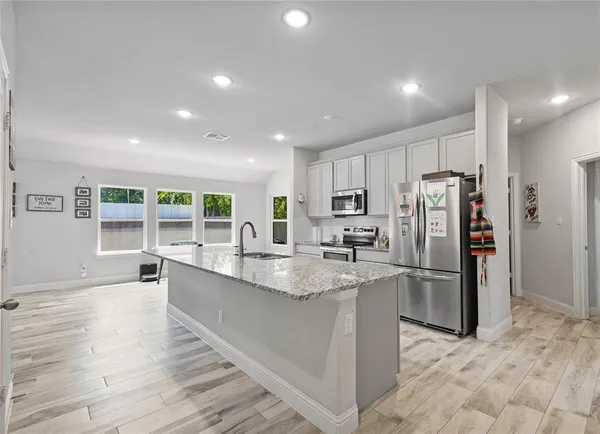 a kitchen with granite countertop refrigerator and chairs