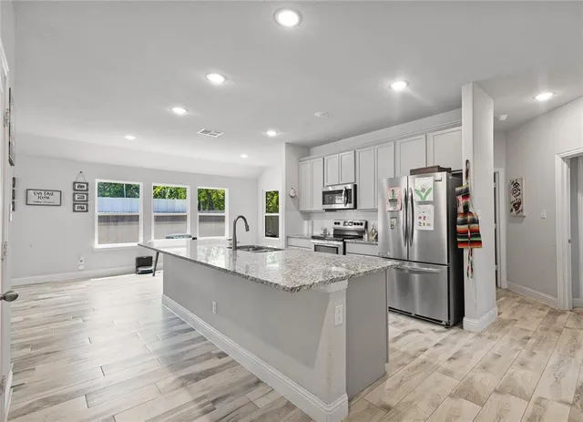 a kitchen with granite countertop refrigerator and chairs