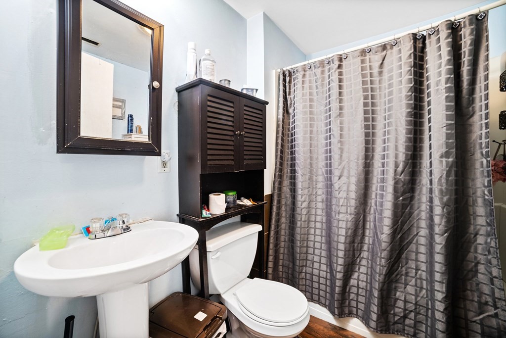 16 Barclay Street Worcester, MA 01604 - Photo 18 of 20 a bathroom with a sink a toilet and shower curtain