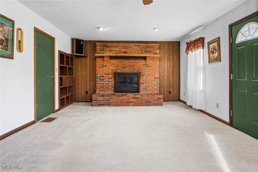 3290 State Rte 534 Geneva, OH 44041 - Photo 10 of 43 Unfurnished living room featuring wood walls, light carpet, and a fireplace
