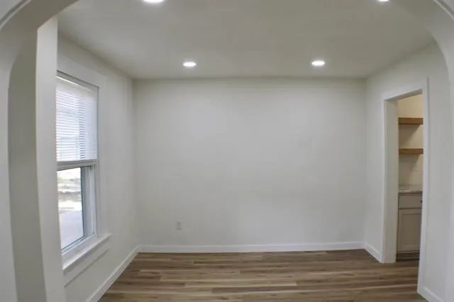 a view of an empty room with wooden floor and a window