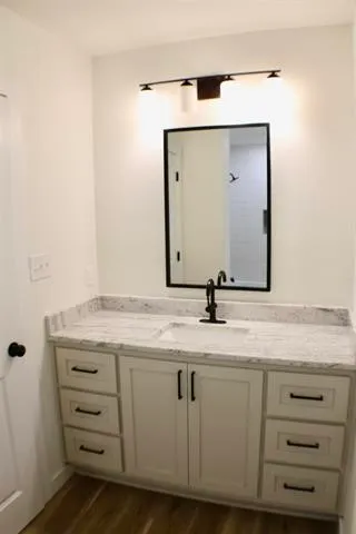 a bathroom with a granite countertop sink and a mirror