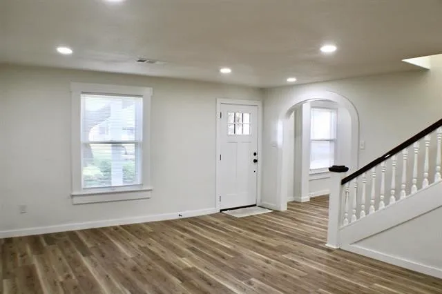 an empty room with wooden floor and windows
