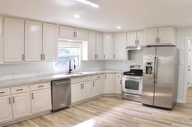 a kitchen with cabinets stainless steel appliances a sink and a window