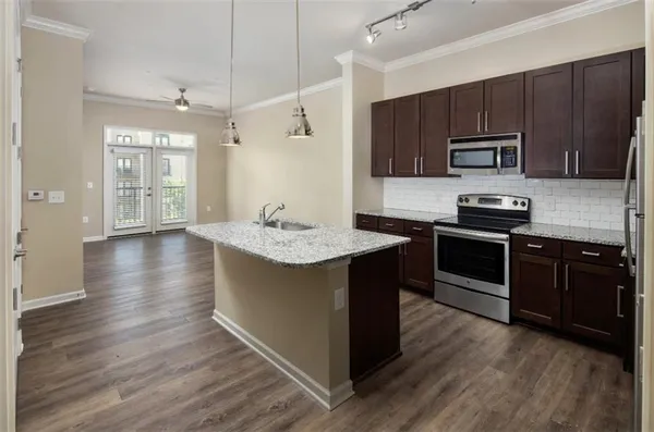a kitchen with kitchen island granite countertop stainless steel appliances and wooden cabinets