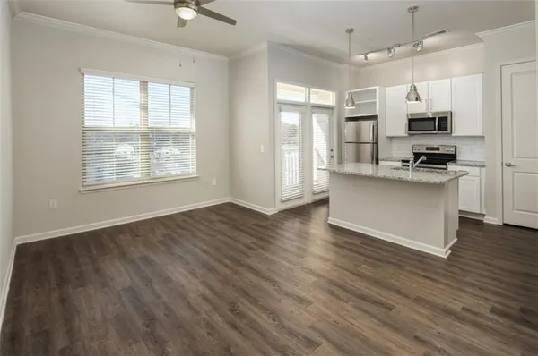 a view of kitchen with stainless steel appliances wooden floor large window and white cabinets