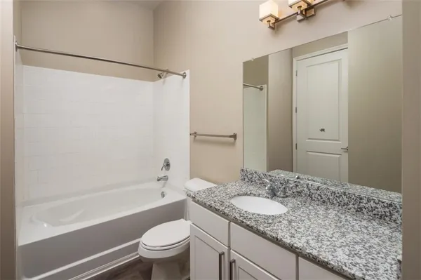 a bathroom with a granite countertop sink toilet and shower