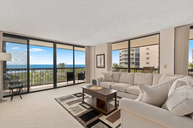 a living room with furniture and a large window with balcony view