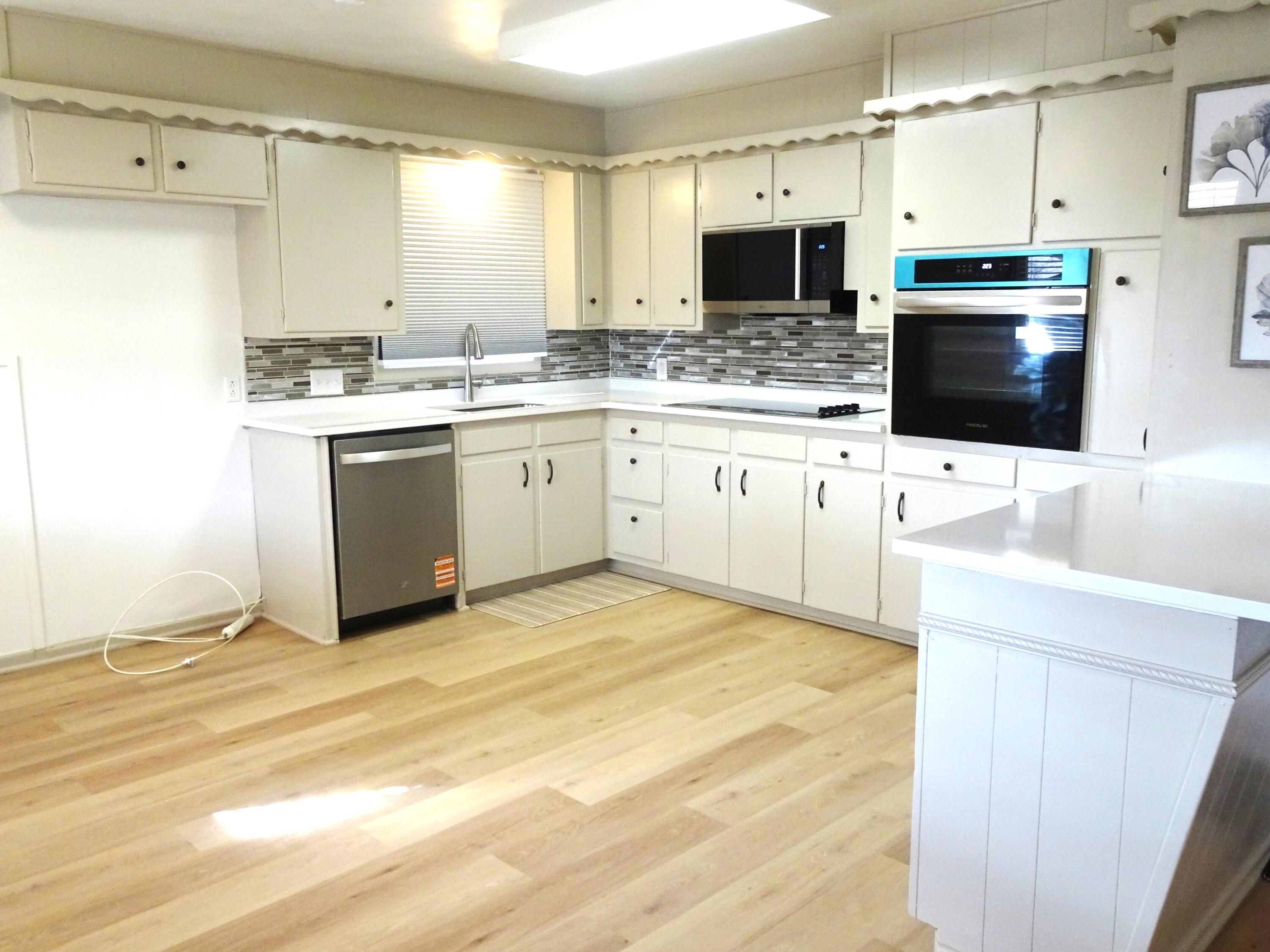 3415 58th Street Lubbock, TX 79413 - Photo 19 of 40 a large white kitchen with granite countertop a sink and a stove top oven with wooden floor