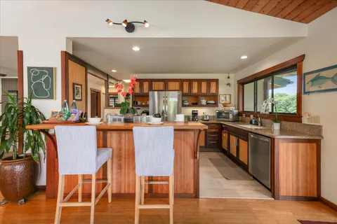 a kitchen with stainless steel appliances kitchen island granite countertop a stove a sink dishwasher and a dining table with wooden floor