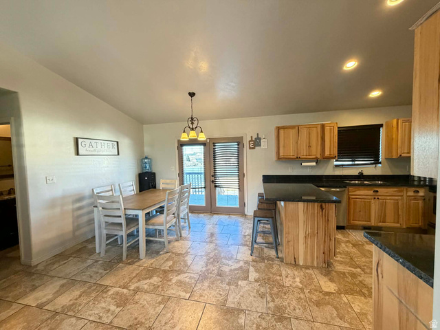 2095 West 4100 North Spring Glen, UT 84526 - Photo 3 of 35 Kitchen with a breakfast bar area, light stone finish floors, lofted ceiling, wood finish cabinets, and hanging light fixtures