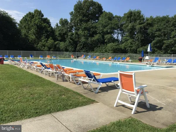 a view of swimming pool with seating area and trees in the background