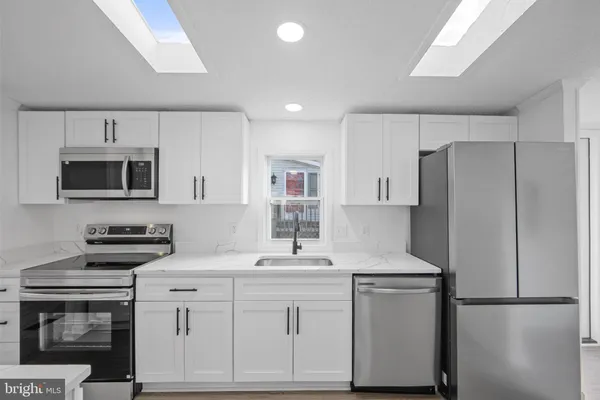 a kitchen with white cabinets sink and stainless steel appliances