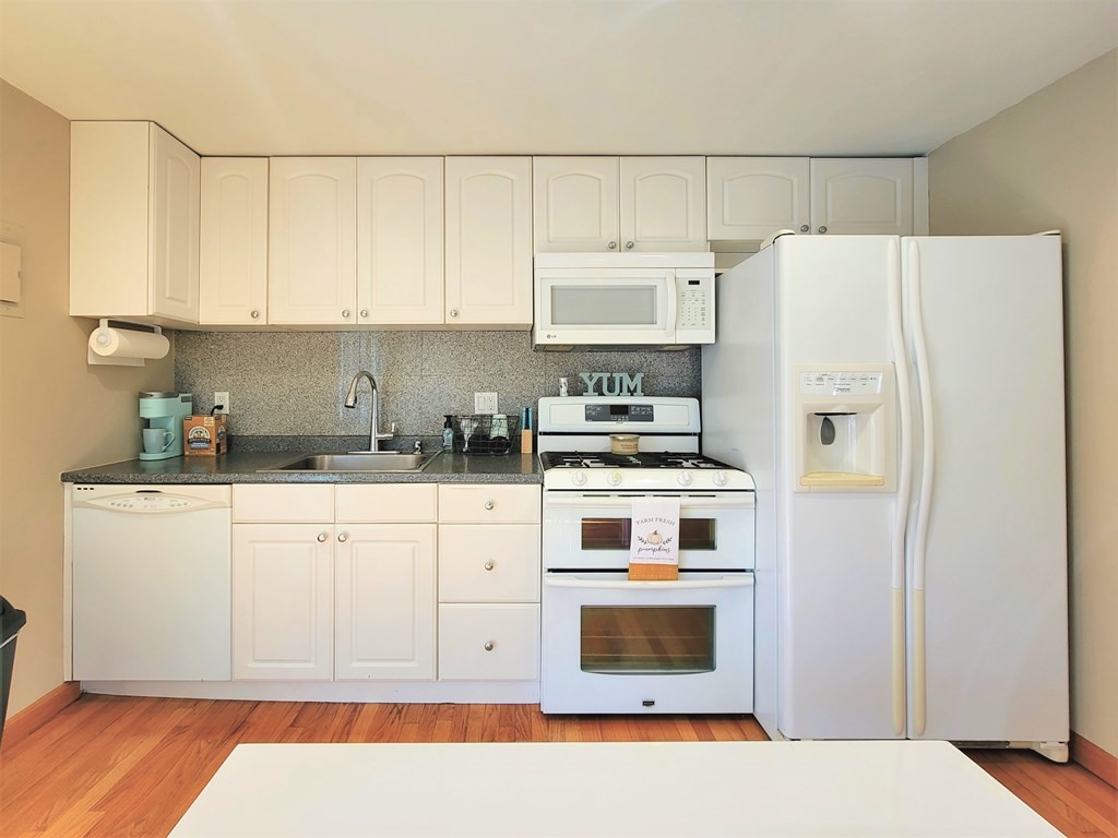 38 Will Drive, Unit 42 Canton, MA 02021 - Photo 6 of 25 a white kitchen with stainless steel appliances a stove a refrigerator and cabinets
