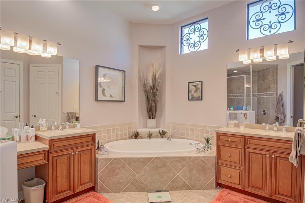3126 Terramar Court Naples, FL 34119 - Photo 17 of 31 a bathroom with double vanity sinks a mirror a vanity a window and a bathtub