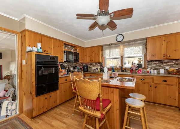 a kitchen with stainless steel appliances granite countertop a stove top oven a refrigerator a dining table and chairs with wooden floor