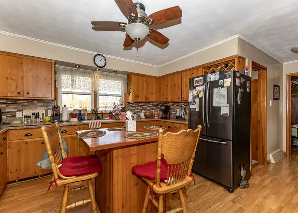 a kitchen with stainless steel appliances granite countertop a dining table chairs refrigerator and sink