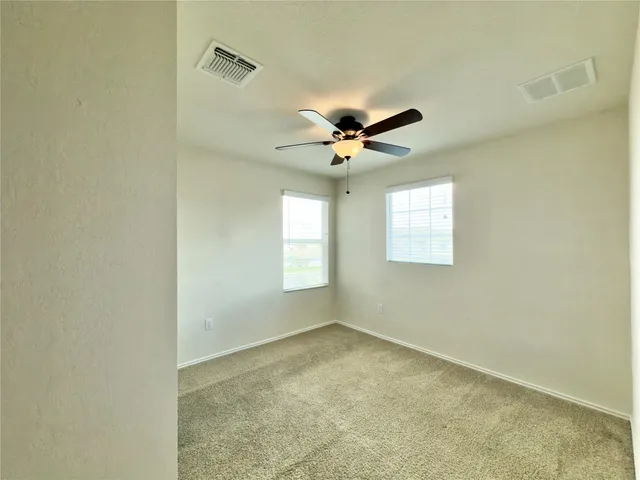 an empty room with windows and fan