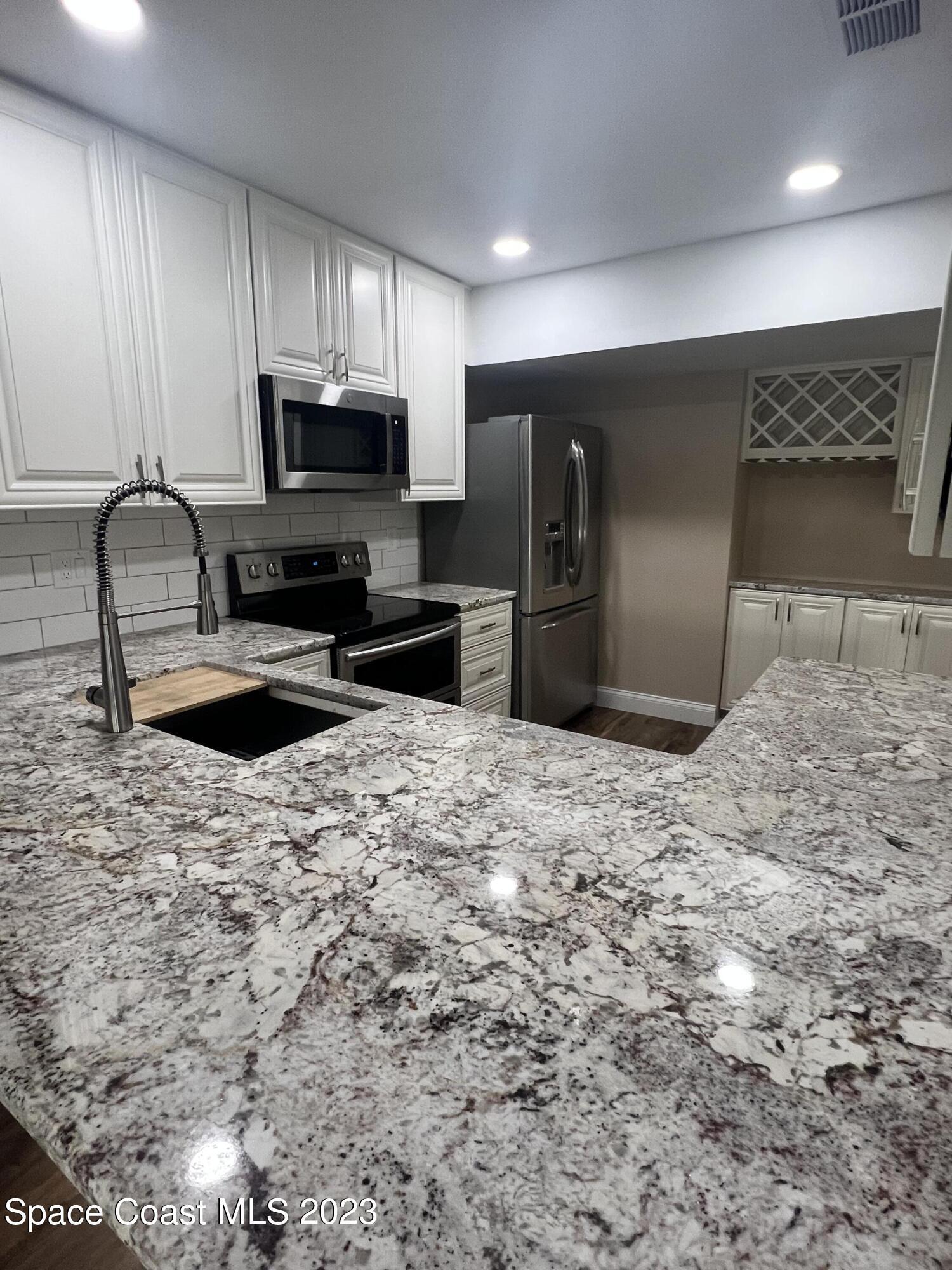 161 Augusta Way Melbourne, FL 32940 - Photo 12 of 26 a kitchen with stainless steel appliances a refrigerator sink stove microwave and cabinets