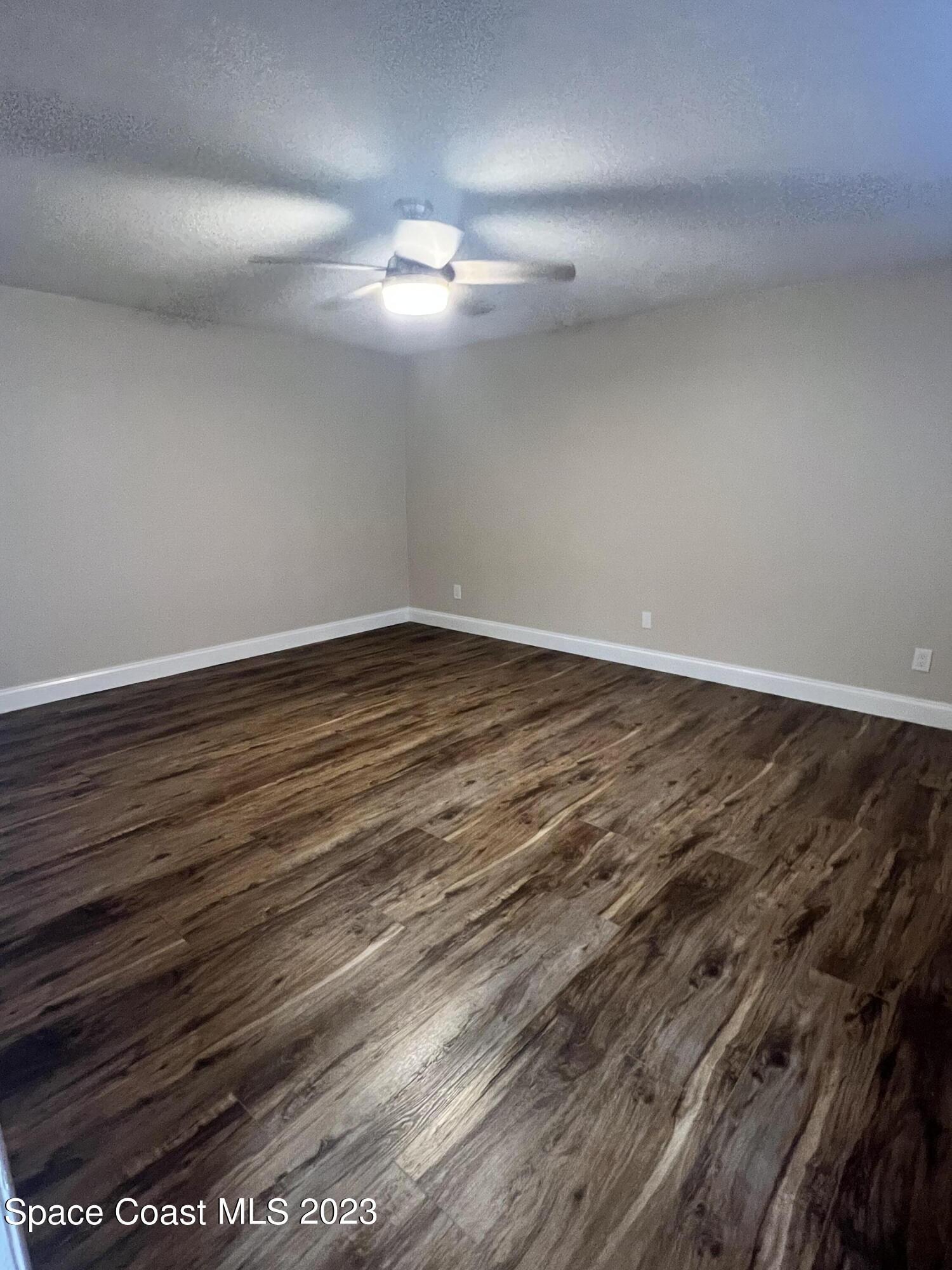 161 Augusta Way Melbourne, FL 32940 - Photo 19 of 26 a view of an empty room with wooden floor and a ceiling fan