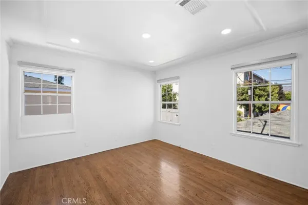 an empty room with wooden floor and windows