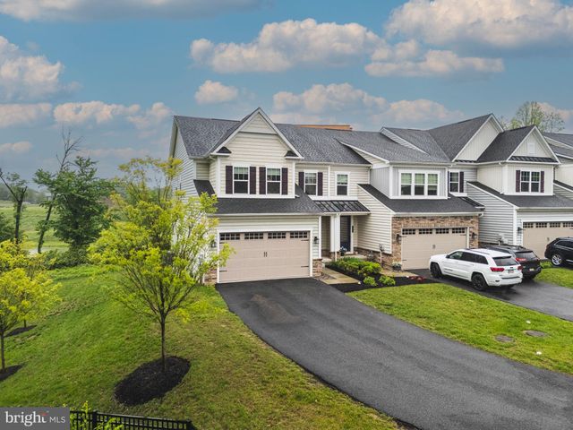 a front view of a house with a garden and tree