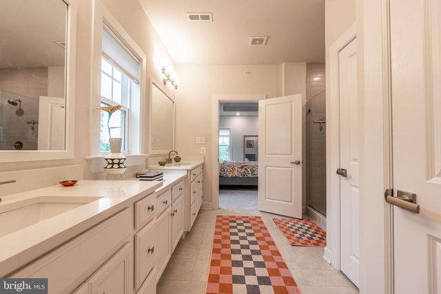 a spacious bathroom with a double vanity sink a mirror and a shower