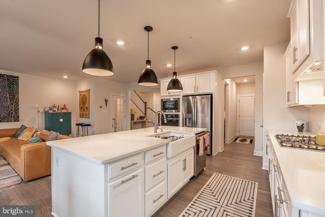 a large white kitchen with a lot of cabinets and wooden floor