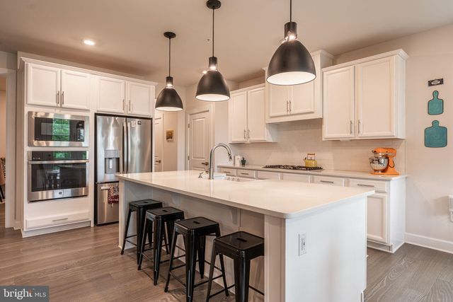 a kitchen with stainless steel appliances granite countertop a sink a stove a refrigerator and island with wooden floor