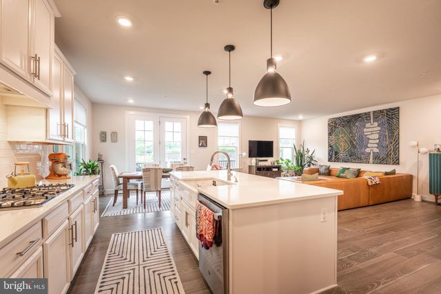 a large kitchen with kitchen island a large counter space a sink appliances and a view of living room