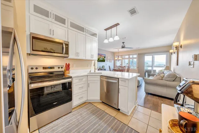 a kitchen with stainless steel appliances granite countertop a stove top oven a sink dishwasher a dining table and chairs with wooden floor