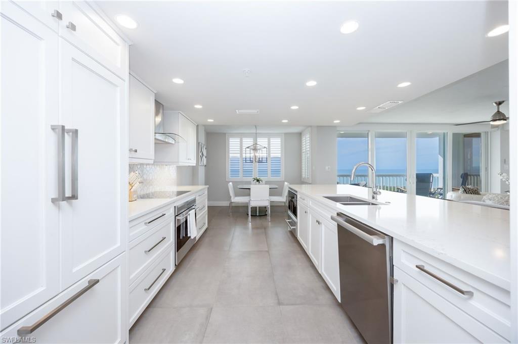 6573 Marissa Loop, Unit 2005 Naples, FL 34108 - Photo 6 of 25 a large kitchen with stainless steel appliances kitchen island a large counter top a stove a chimney a sink and a refrigerator