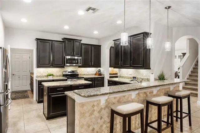 a kitchen with stainless steel appliances granite countertop a kitchen island a stove and a refrigerator