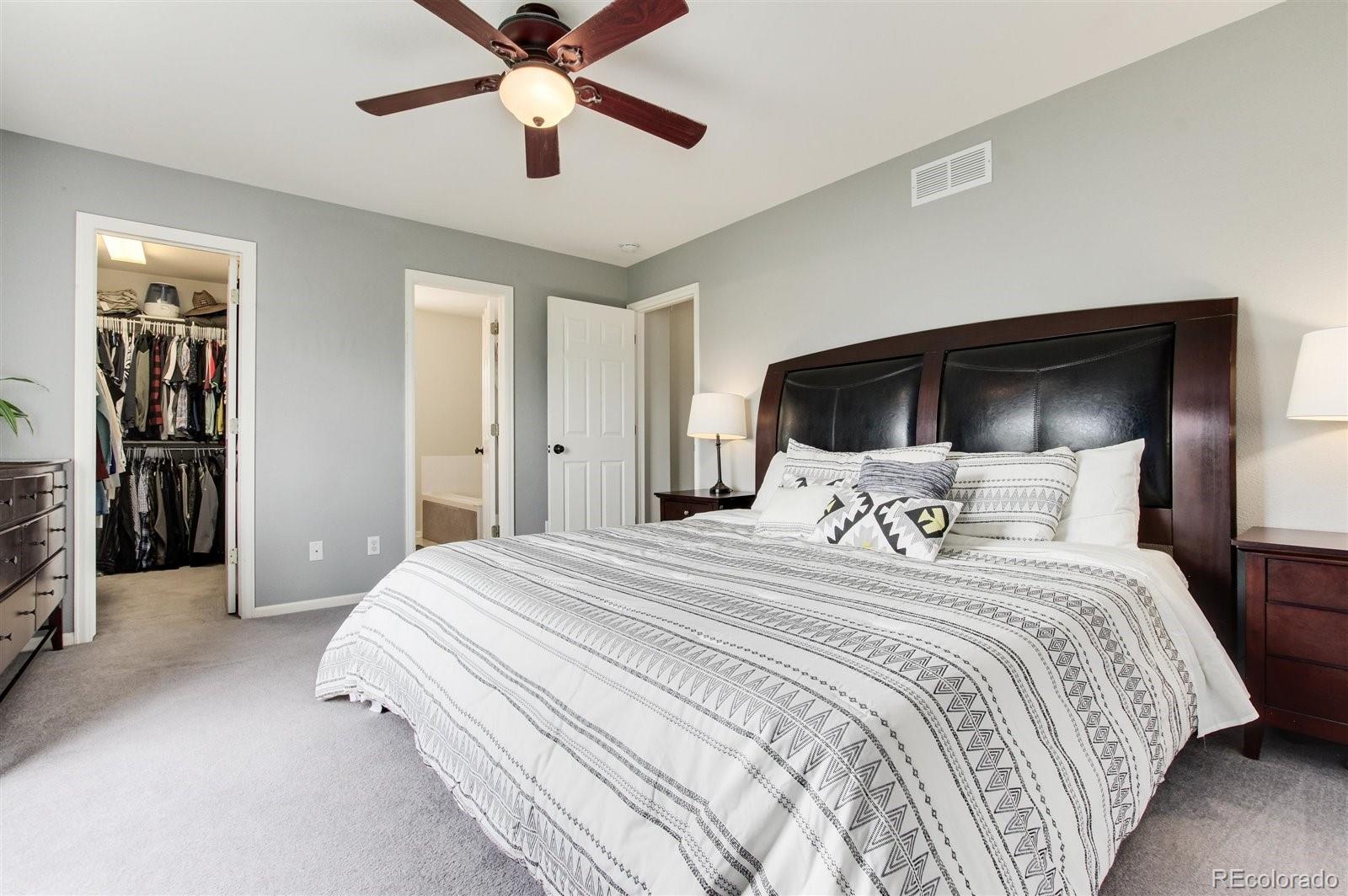 9701 Moss Rose Circle Highlands Ranch, CO 80129 - Photo 28 of 40 a bedroom with a large bed and a chandelier