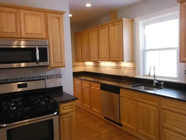 a kitchen with granite countertop a sink stove and microwave