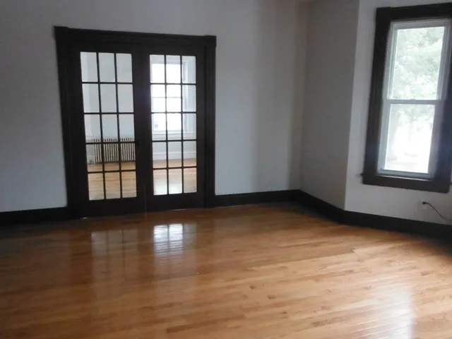 an empty room with wooden floor and windows