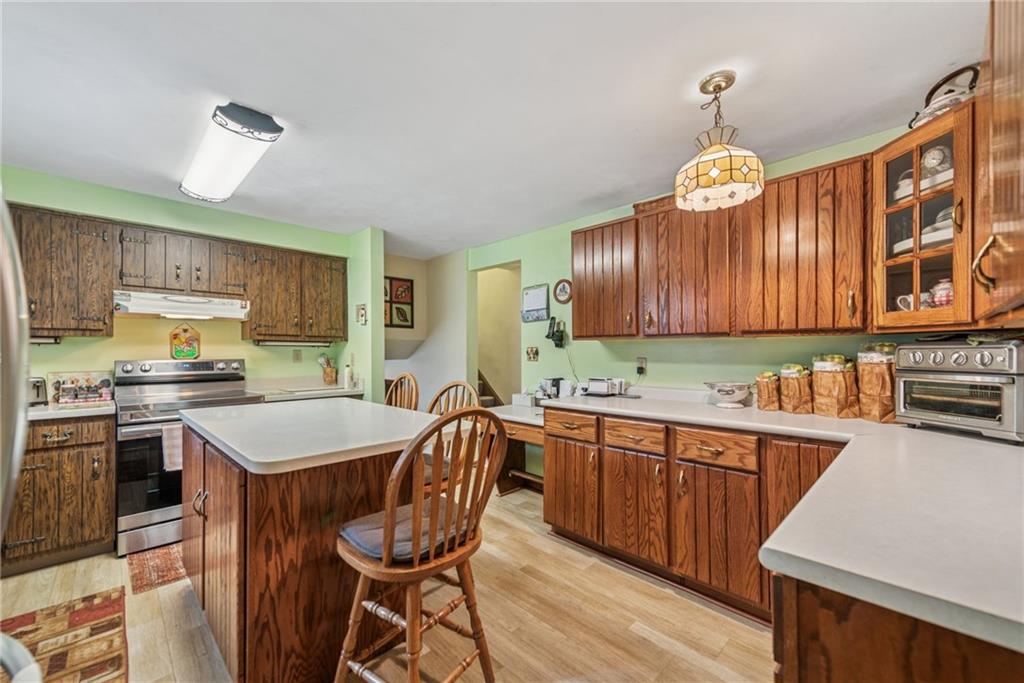 982 Braddock Road Pittsburgh, PA 15221 - Photo 10 of 32 a kitchen with stainless steel appliances a stove a sink dishwasher and a refrigerator with wooden floor