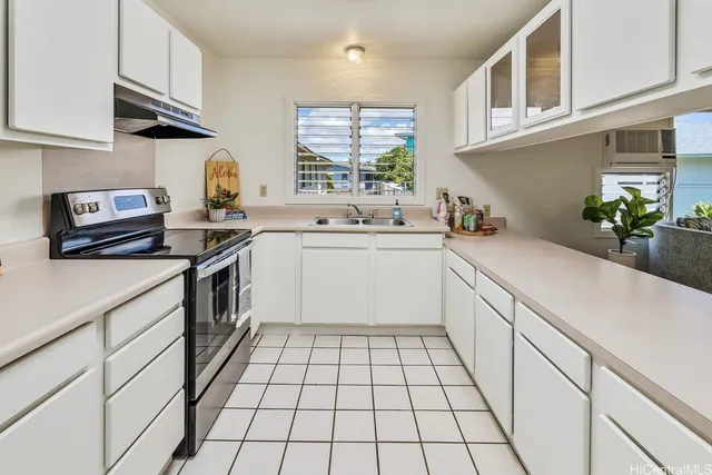 a kitchen with a sink dishwasher stove and white cabinets