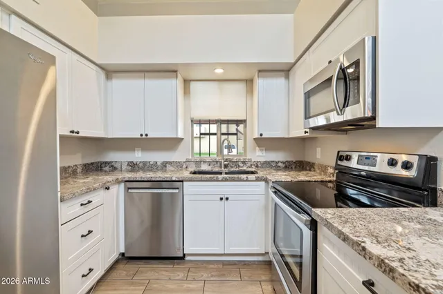 a kitchen with granite countertop cabinets stainless steel appliances and a sink