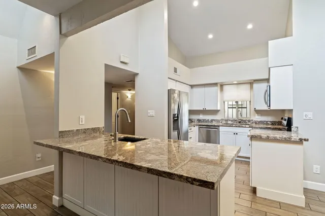 a kitchen with kitchen island granite countertop a sink cabinets and stainless steel appliances