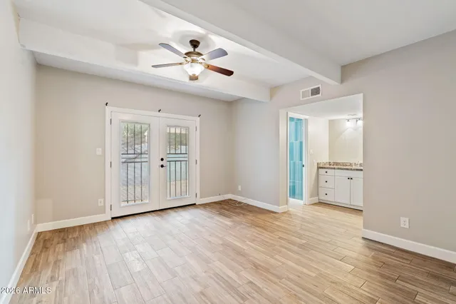 an empty room with wooden floor fan and windows