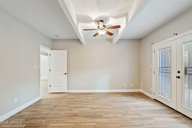 a view of an empty room with window and wooden floor