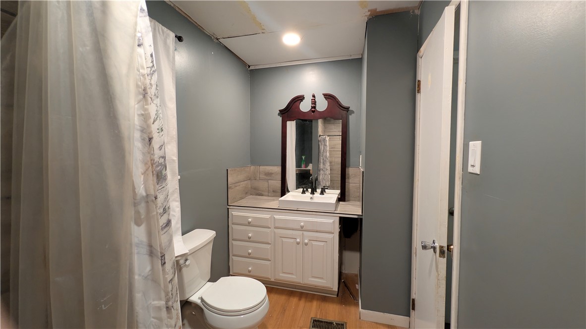 194 Pine Valley Loop Houston, AR 72070 - Photo 9 of 21 Bathroom featuring wood-finish flooring, a white vanity with built-in cabinetry, and a rectangular vessel sink with a black faucet