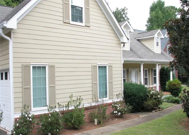 a view of a white house with a small yard and plants