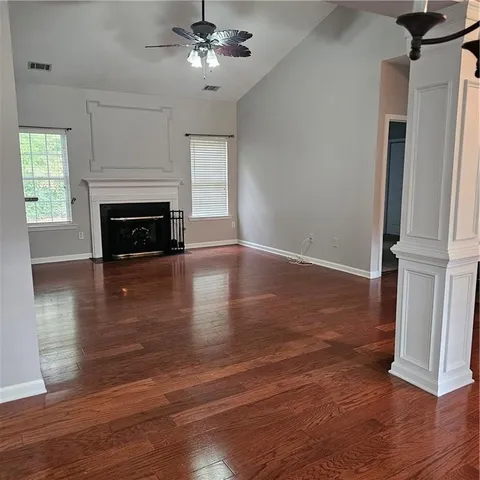an empty room with wooden floor fireplace and windows