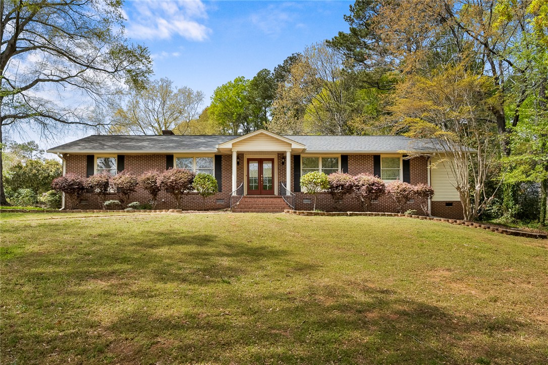 This charming home features a classic brick exterior and a welcoming facade, framed by lush greenery.